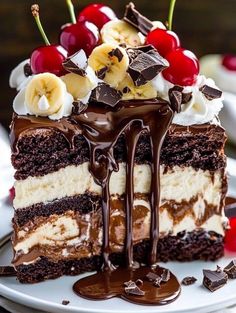 a piece of cake on a plate with chocolate sauce and bananas, cherries, and whipped cream