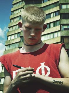 a young boy writing on his hand with a pen in front of a tall building