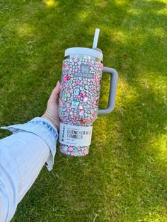 someone is holding up a cup with sprinkles on it in the grass