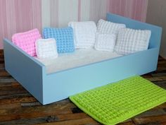 there is a blue box with crocheted pillows on it and a green rug