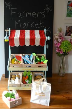 a farmers market stand with baskets full of fruits and vegetables next to it on a wooden table