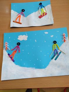 two children's art work made out of paper with skis and snowmen