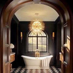 an ornate bathroom with black and white checkered flooring, chandelier above the bathtub