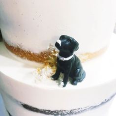 a black dog figurine sitting on top of a white cake