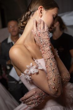 a woman in a pink dress with her hands on her face and arms covered by sequins