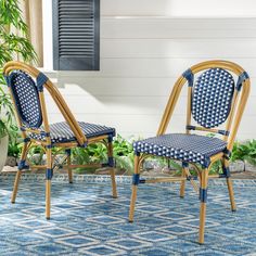 two chairs sitting on top of a blue and white rug next to a planter