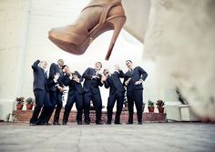 a group of men in suits and high heels standing next to each other with their hands together