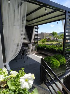 an outdoor patio with white flowers and greenery on the balcony area in front of it