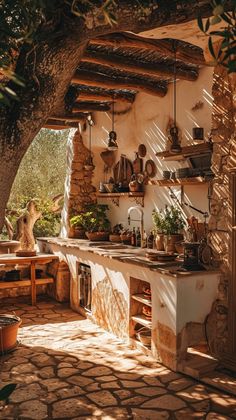 an outdoor kitchen with pots and pans hanging from the ceiling, surrounded by stone walls