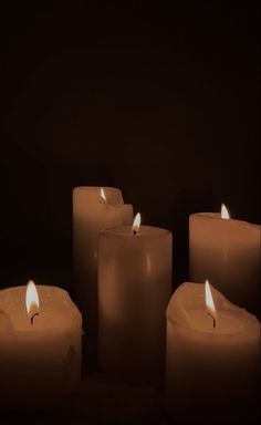 several lit candles in the dark with one candle on each side and two are white