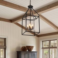 a chandelier hanging from the ceiling in a room with wooden floors and white walls