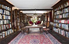 a room filled with lots of books and furniture next to a rug on the floor