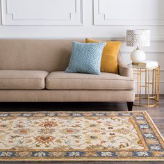 a living room with a couch, rug and lamp on the side table in front of it