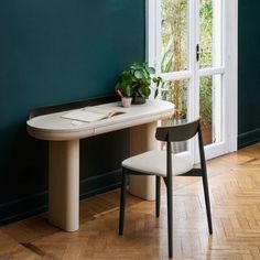 a table with a plant on it next to a chair in front of a window