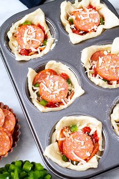 some food is in a muffin tin on a table with green peppers and other ingredients