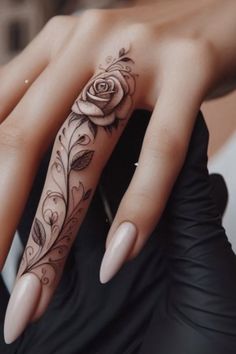 a woman's hand with a rose tattoo on the middle finger and an intricate design