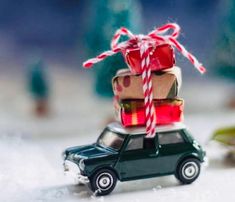 a toy car with presents tied to it sitting on top of a snow covered ground