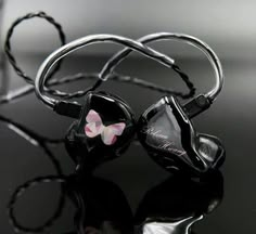 a pair of black and pink earbuds sitting on top of a reflective surface