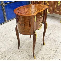 an ornately decorated wooden table with drawers on the top and bottom, sitting in a room