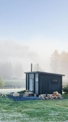 a small black building sitting on top of a lush green field