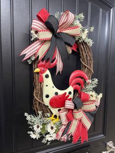 a rooster wreath with red, white and black bows hanging on the front door handle