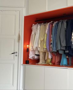 an open closet with clothes hanging on the wall and candles in the corner next to it