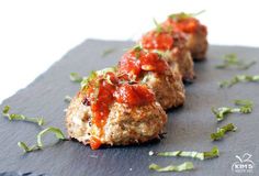 two meatballs covered in marinara sauce on top of a cutting board with the words turkey zucchini meatballs