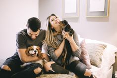 a man and woman sitting on a bed with their dogs