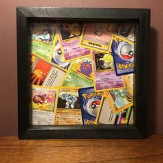 a wooden table topped with lots of pokemon cards on top of a wall next to a pink wall