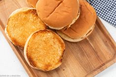 three hamburgers sitting on top of a wooden cutting board