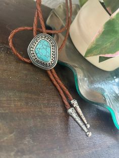 This awesome bolo tie has a southwestern design and agate centerpiece. Handmade in our shop. The cord is genuine brown leather. Our bolos pair nicely with many of our belt buckles! They make wonderful gifts. The western bolo tie rope length is 40'' ; charm agate stone pendant size is 1 1/4'' x 1 1 /2'' Turquoise Bolo Tie, Western Bolo Tie, Mens Leather Necklace, Homecoming Outfit, Southwestern Design, Tie Gifts, Bolo Tie, Cow Boy, Men's Necklace