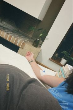 a woman laying on top of a bed next to a fireplace