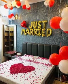 a bedroom decorated with balloons and confetti on the bed for a wedding day