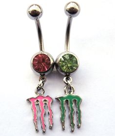 two different colored dangling belly rings with monster teeth on each one and a green, red, and pink crystal stone in the middle