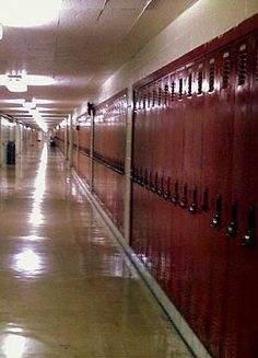 an empty hallway with red lockers on the walls