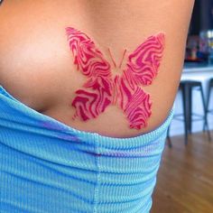 a woman's stomach with a pink butterfly tattoo on her back and the words ink by kai