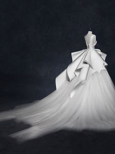 the back of a white wedding dress on display in front of a black background with text that reads, bridally com