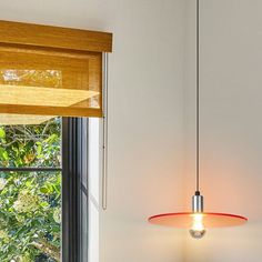 a lamp hanging from the ceiling next to a window in a room with white walls