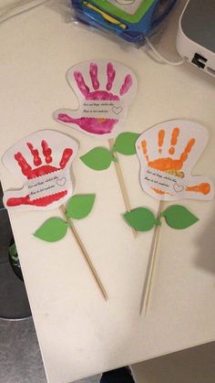 three handprinted flowers on top of a white table