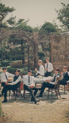 a group of young men sitting around a table in formal dress clothes with ties on