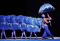 the dancers are dressed in blue and holding an umbrella over their heads as they walk on stage