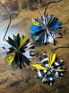 three different colored paper flowers on a wooden table with wires attached to them and string