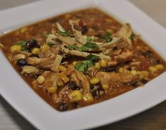 a white square bowl filled with chicken and corn soup