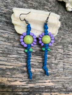 Flowers comprised of a green stone center and purple glass beads as petals with green glass bead leaves stitched into blue hemp. Flowers measure 7.5 inches across with a total length of 2.75 inches. Shell Wreath, Beaded Leaf, Hippie Flowers, Purple Glass, Leather Sheath, Green Stone, Glass Bead, Flower Earrings, Green Glass