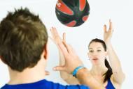 a man and woman playing with a ball on a white wall in front of them