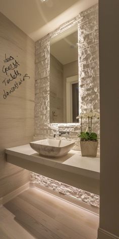 a bathroom sink sitting under a mirror next to a counter top with a plant in it