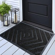 a black door mat sitting on top of a wooden floor next to a potted plant