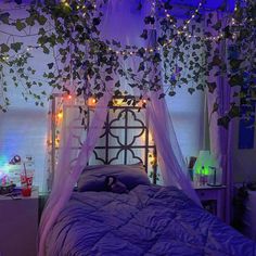 an unmade bed with purple sheets and lights hanging from the ceiling