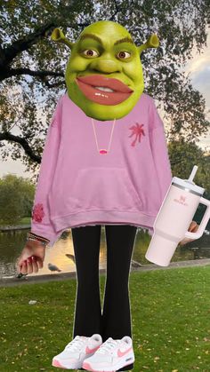 a woman in pink shirt and black leggings standing next to a green creature