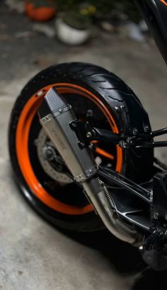 an orange and black motorcycle is parked on the street with it's front tire